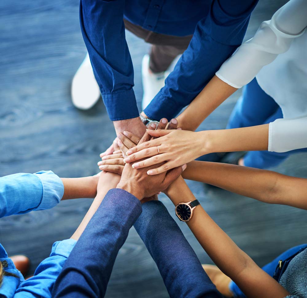 Mehrere Personen halten als Team die Hände aufeinander als Geste des Zusammenhaltes.