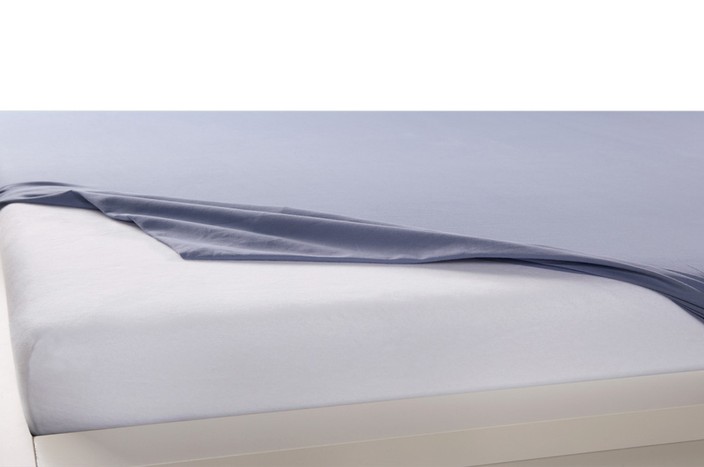 Weißer Matratzenschoner unter einem Spannbetttuch schützt die Matratze
