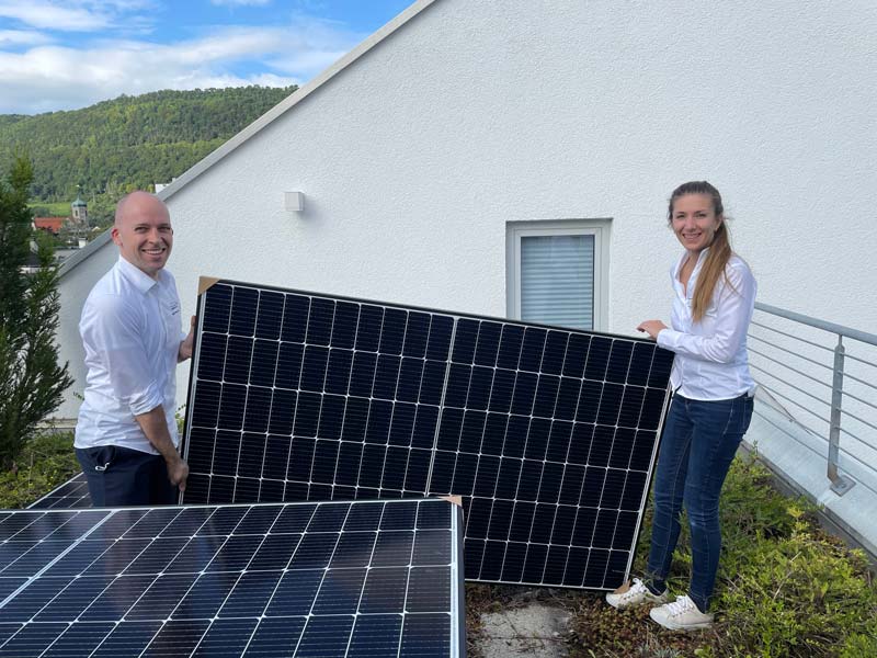 Iulia und Daniel mit einem Photovoltaik-Modul auf dem Dach des Bettenfachgeschäftes in Geislingen.